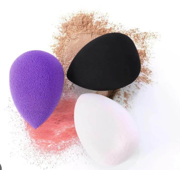 Purple, black, and white beauty blender sponges on face powder .