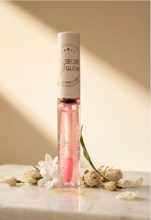"Secret Glow beauty product. Clear pink lip gloss surrounded by white flowers"